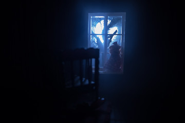 Old creepy eerie baby crib near window in dark room. Scary baby silhouette in dark. A realistic...