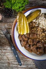 Beef stew served with barley and pickled cucumber.