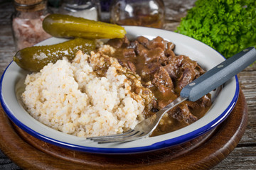 Beef stew served with barley and pickled cucumber.