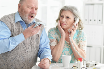 Portrait of ill senior couple at home calling doctor
