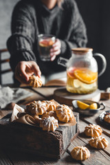 A woman reaches for a cake and drinks grapefruit tea. Healthy drink.