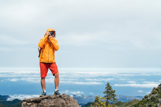 Young adult caucasian man dressed sporty clothes with backpack taking a picture from Pico Ruivo mount 1861m - the highest peak on the Madeira Island,Portugal. Active vacation concept image.