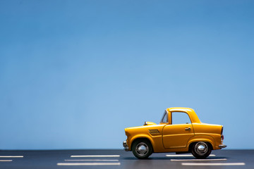 Fototapeta na wymiar Yellow toy car on a blue background.