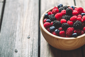 raspberries and blackberries on a wooden background in vintage style. Cutting board