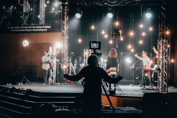 Camera Operator worshipping with the praise band for online church - obrazy, fototapety, plakaty