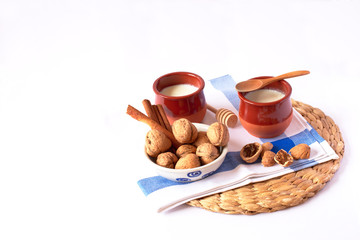 Natural goat milk curd with cinnamon, walnuts and honey in clay glass and wooden spoon