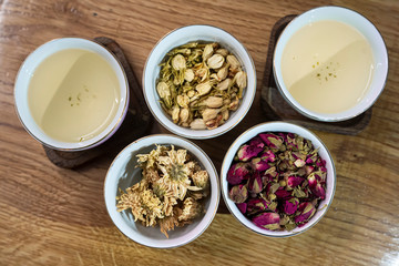 Tea additives in white cups. Wooden table. Tea ceremony.