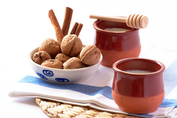 Natural goat milk curd with cinnamon, walnuts and honey in clay glass and wooden spoon