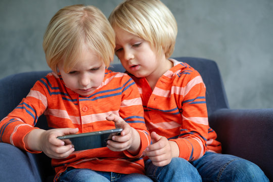 Brothers are watching or playing or learning something in a smartphone