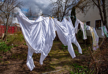 Two medical coats are drying on a rope in the yard.