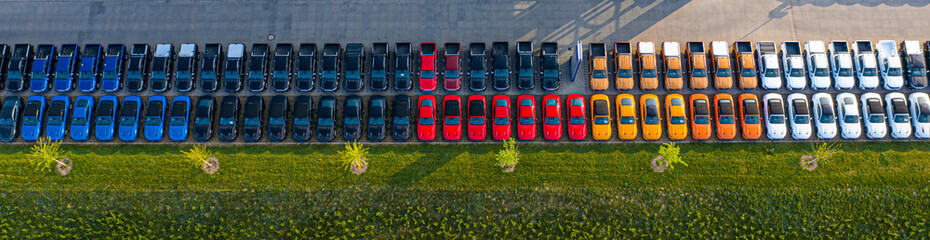 Aerial view of a car distribution centre, new cars parked in rows on a lot ready for sale.