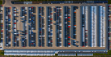 Aerial view of a car distribution centre, new cars parked in rows on a lot ready for sale.