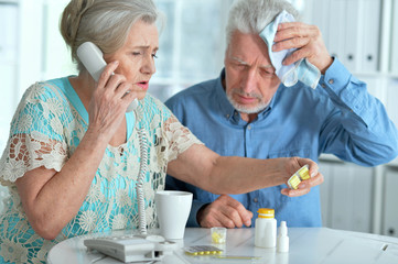Close up portrait of sick senior couple calling to doctor