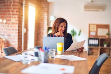 Middle age beautiful businesswoman smiling happy and confident. Sitting on chair working in a desk at the office