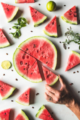 Red slices of ripe watermelon with mint leaves and lime slices on a white background. Top view