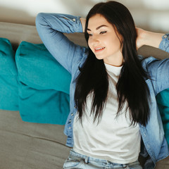 Young woman relaxing on a couch in living room. Home, comfort, dreaming and harmony