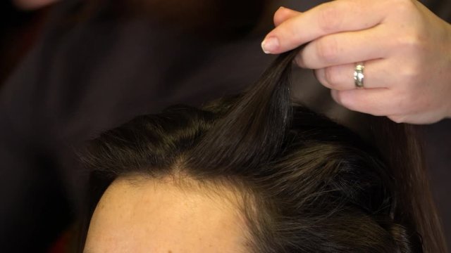 The stylist straightens strands of hair with a comb