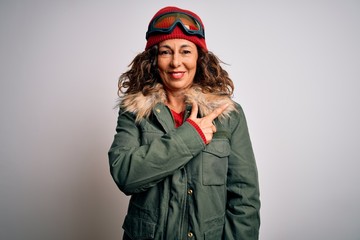 Middle age skier woman wearing snow sportswear and ski goggles over white background cheerful with a smile of face pointing with hand and finger up to the side with happy and natural expression