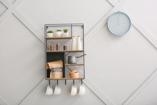 Shelf with kitchenware on light wall