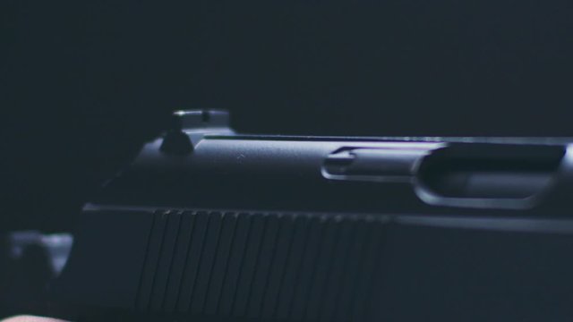 man shoots with air pistol on black background macro