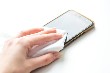Close up view of man hand using antibacterial wet wipe for disinfecting smartphone touch screen. Antiseptic and disinfection of objects in the house