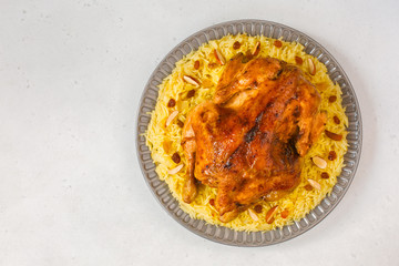 Kabsa - arabian dish made of long grain basmati rice, whole chicken, onion, spices: cardamom, saffron, cinnamon, bay leaves.  Decorated with almonds and raisins. Saudi Arabia food.