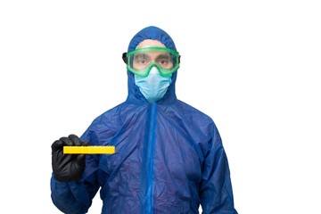 a man in a protective blue suit and mask holds a yellow sign