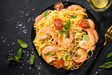 Pasta seafood with shrimp on black table.