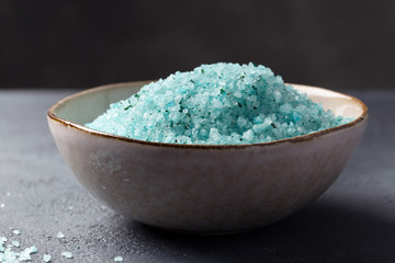 Home Spa. Blue sea salt with seaweed for the body in a bowl on a dark background. Space for text.