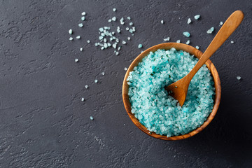Blue sea salt with seaweed for the body in a bowl on a dark table. Top view. Space for text.