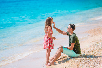 Father applying sun protection cream to his daughter at tropical beach