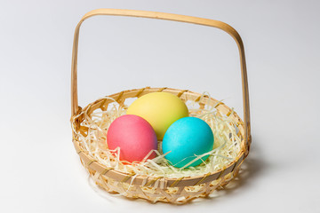 Colorful Easter eggs in a basket isolated on white background. Close-up, holiday postcard idea