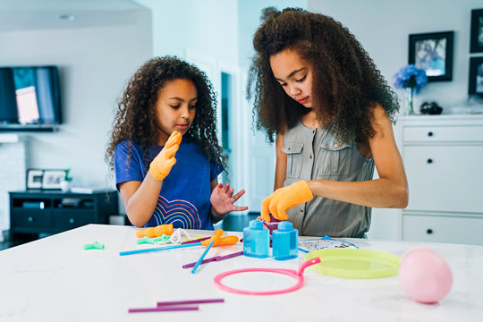 Girls playing together at kitchen counter with bubble stuff