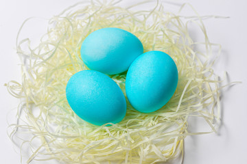 Blue Easter eggs in nest isolated on white background. Happy Easter card, close-up
