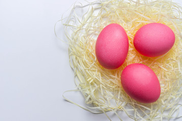 Naklejka na ściany i meble Pink Easter eggs in nest isolated on white background. Happy Easter card, close-up, copy space