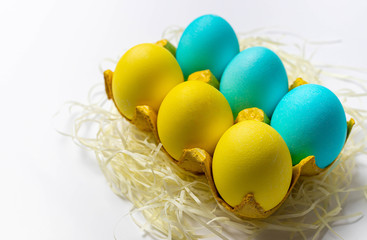 Colorful Easter eggs in yellow paper egg tray isolated on white background. Postcard idea, top view, close-up