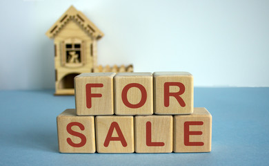 Cubes form the words for sale in front of a miniature house.