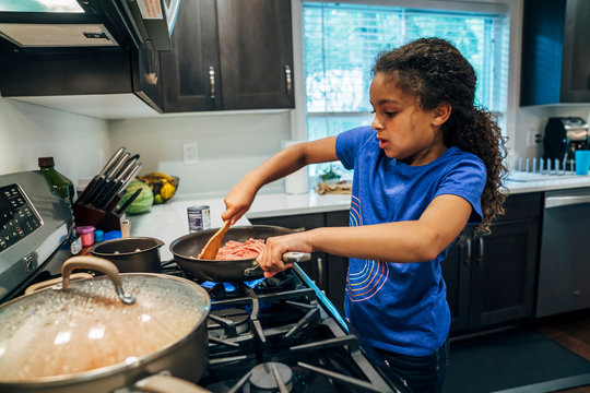 Girl cooking meal at stove in home kitchen