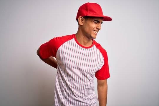 Young handsome african american sportsman wearing striped baseball t-shirt and cap Suffering of backache, touching back with hand, muscular pain