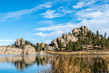 Naklejka premium Rock Formation And Evergreen Trees Next To Lake