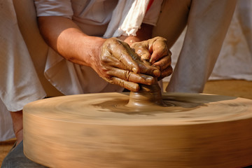 Pottery - skilled hands of potter shaping the clay on potter wheel making small bottle. Pot throwing. Manufacturing traditional handicraft Indian jar, pot, jug. Shilpgram, Udaipur, Rajasthan, India