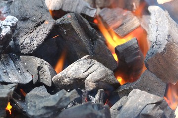 In selective focus firewood with hot coals from burning small wood logs in a stove 