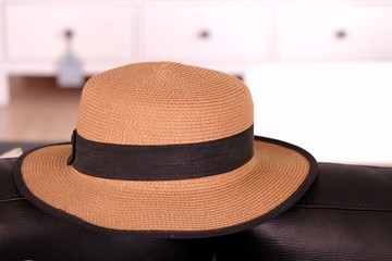 Close up a brown straw hat on a black cough with copy space for a lady travelling concept 