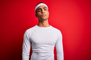 Young handsome african american sportsman wearing sportswear over red background looking sleepy and tired, exhausted for fatigue and hangover, lazy eyes in the morning.