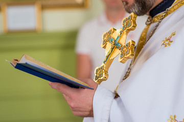 Priest holds holy cross and bible in orthodox church