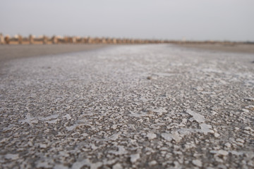 Sandy bottom of a dried reservoir with cracks and salt crystals.