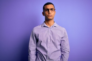 Obraz premium Handsome african american man wearing striped shirt and glasses over purple background depressed and worry for distress, crying angry and afraid. Sad expression.