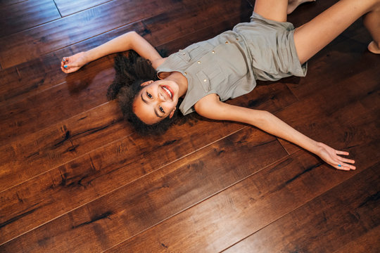 Smiling girl laying on wood floor in home