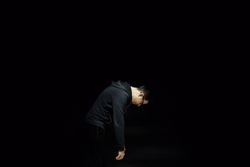 Man bending on black background