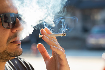 A smoker exhaling a cloud of secondhand smoke from his cigarette.